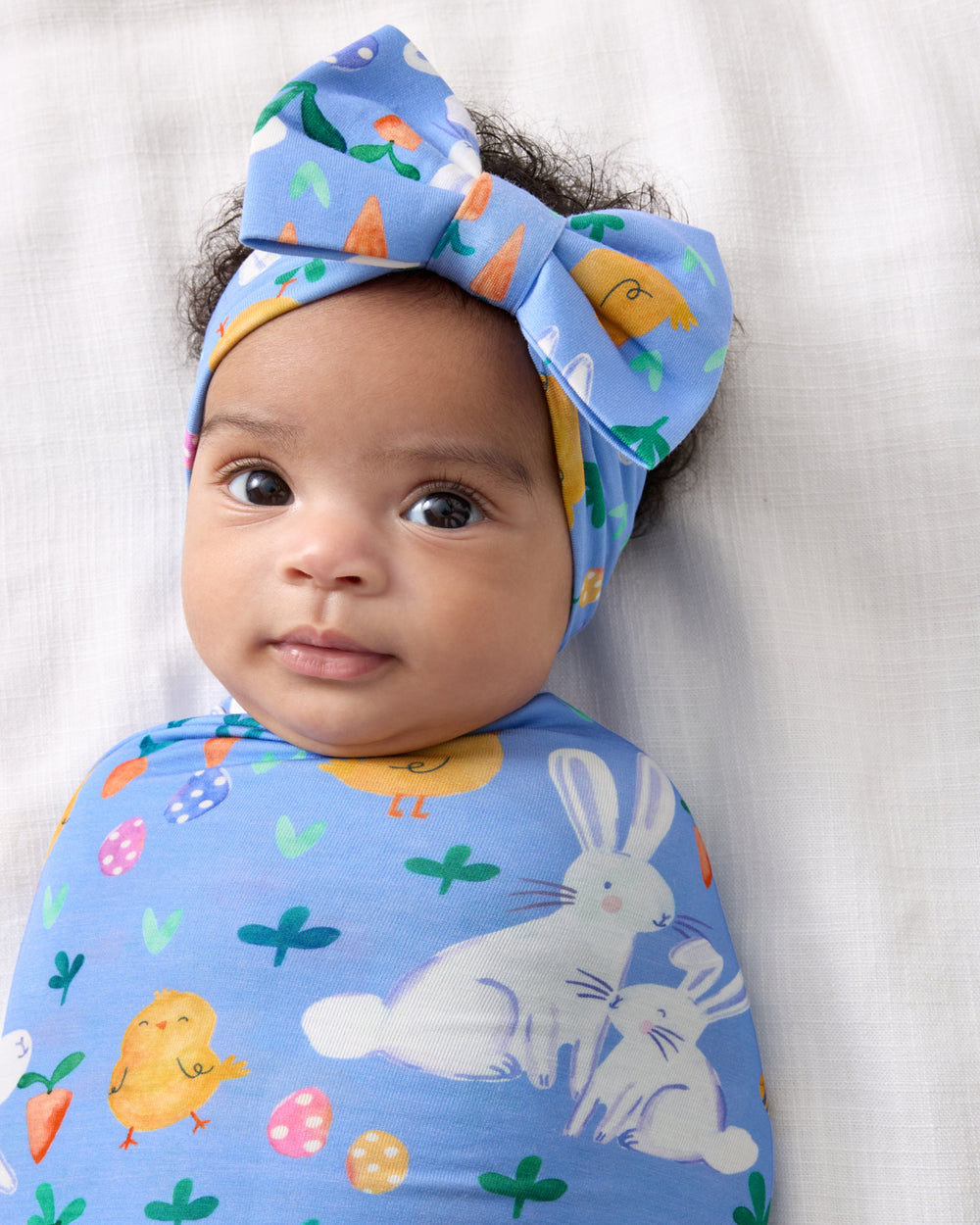 Baby swaddled in the Bunny Patch Swaddle & Luxe Bow Headband Set