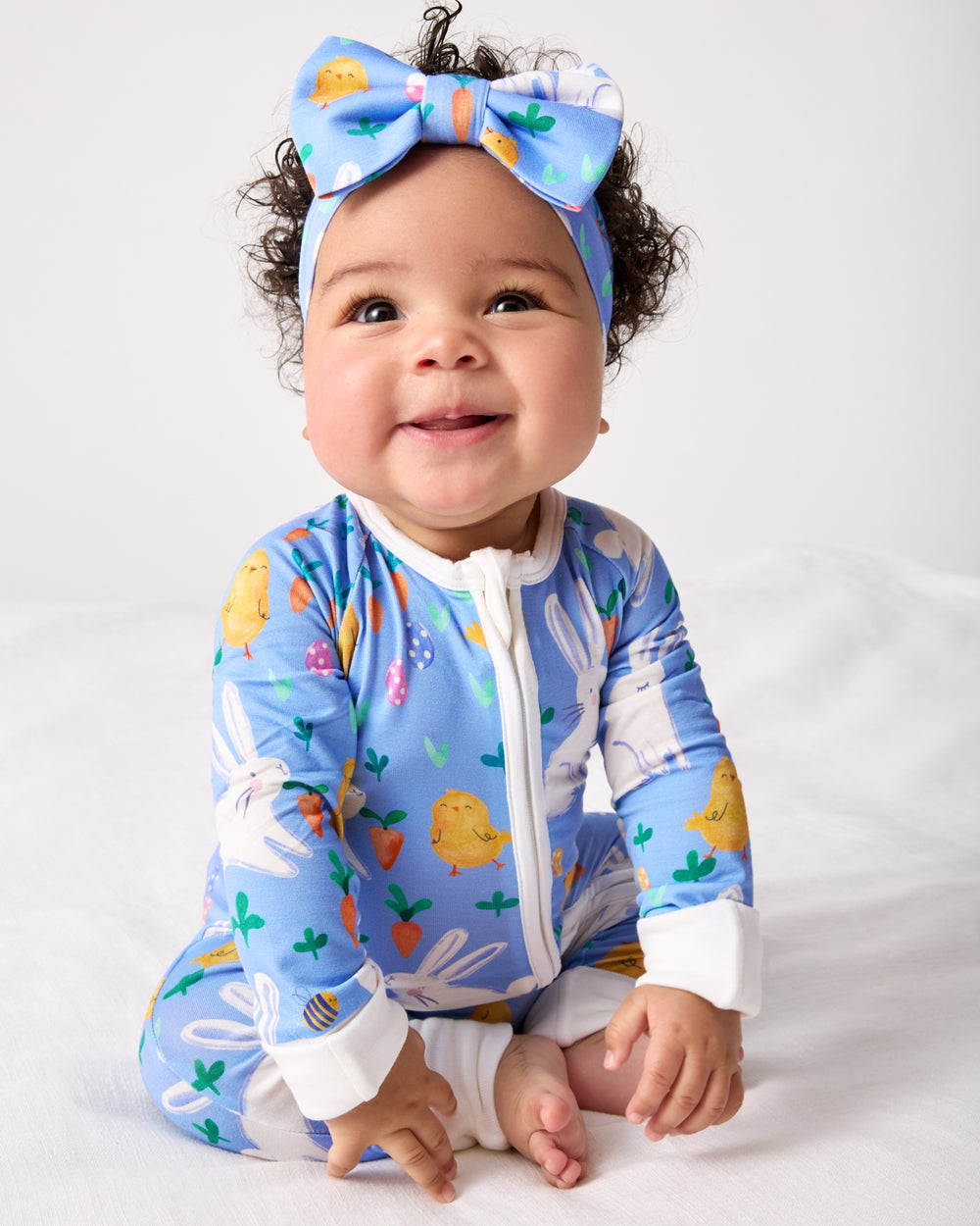 Sitting baby wearing the 
Bunny Patch Zippy and Luxe Bow Headband