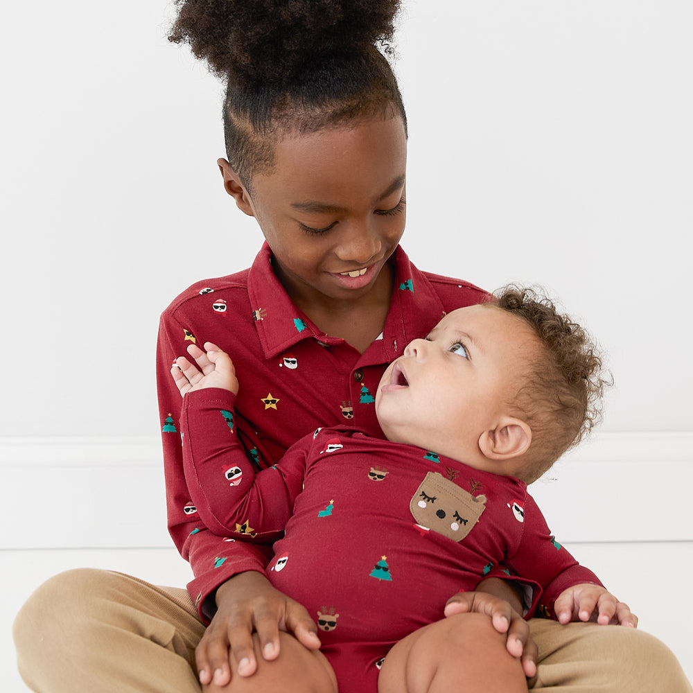 Two siblings sitting on the ground wearing matching Cool Christmas Play styles