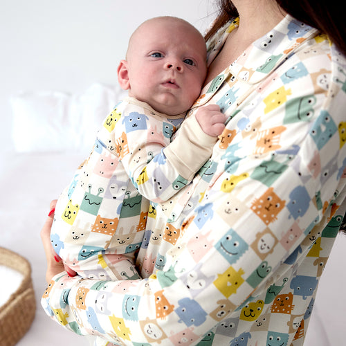 Mother holding her infant, both wearing matching Check Mates pajamas