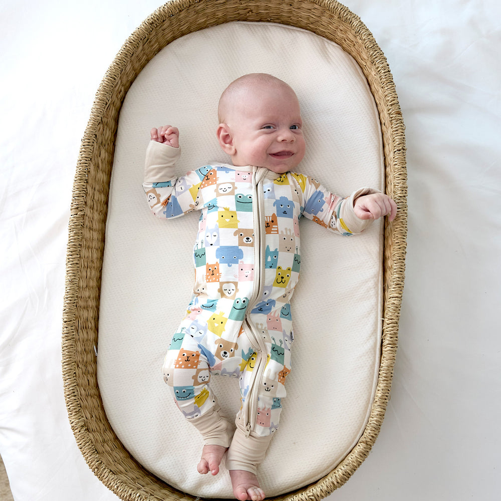 baby laying in basket smiling wearing the check mates zippy