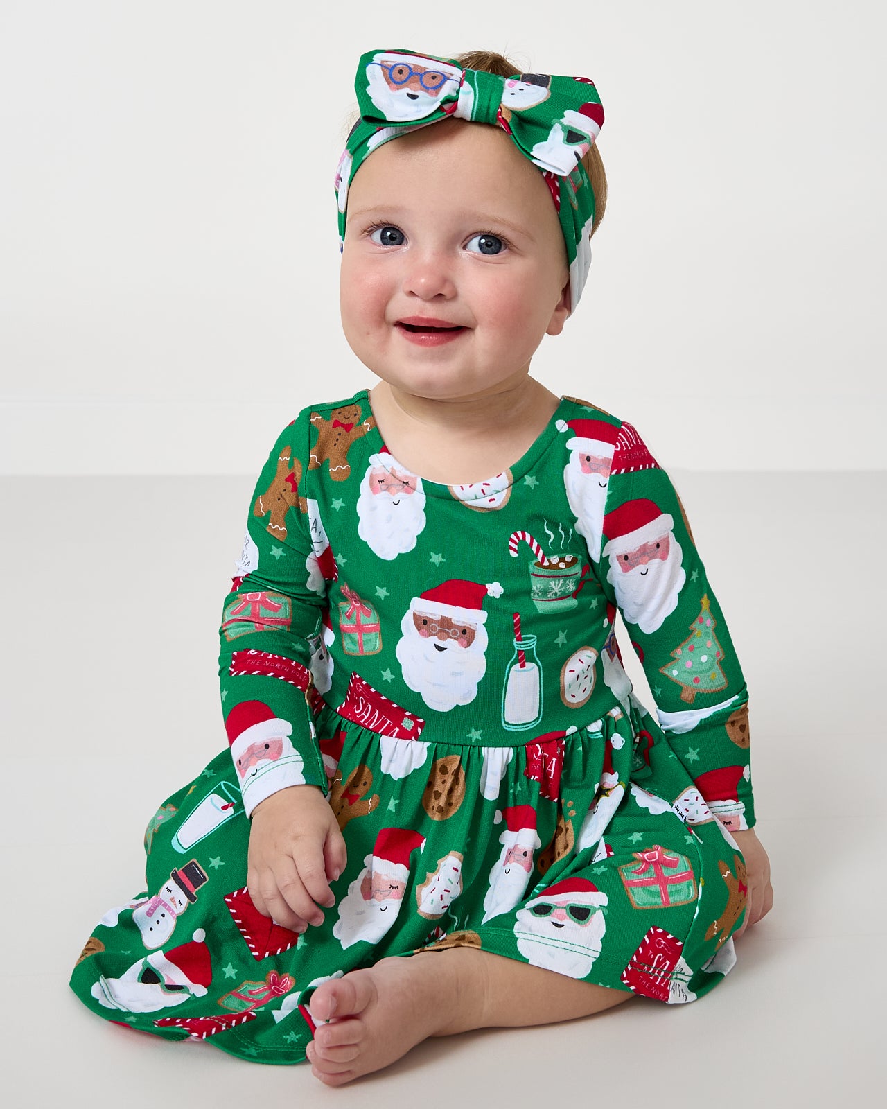 Sitting baby wearing the Cookies for Santa Bow Back Skater Dress with Bodysuit