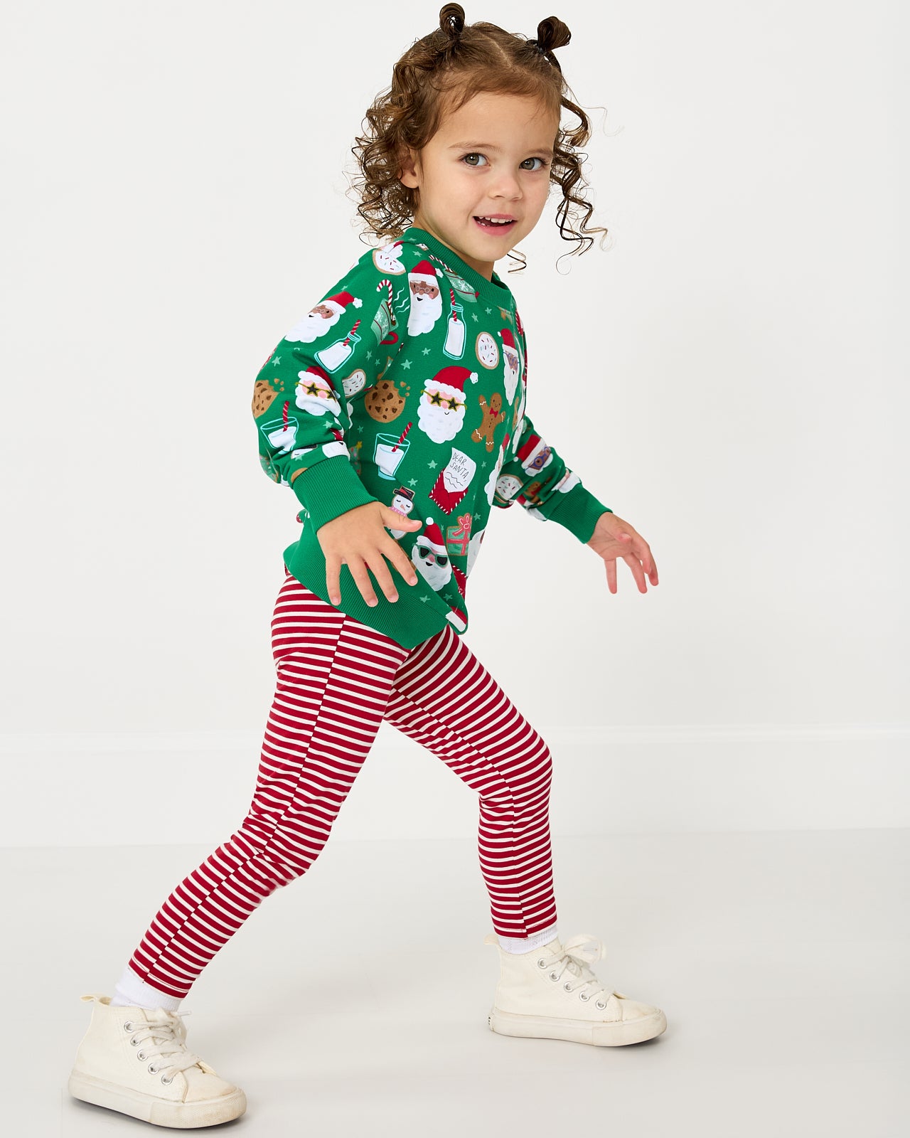 Child in motion wearing the Cookies for Santa Crewneck Sweatshirt with red striped leggings