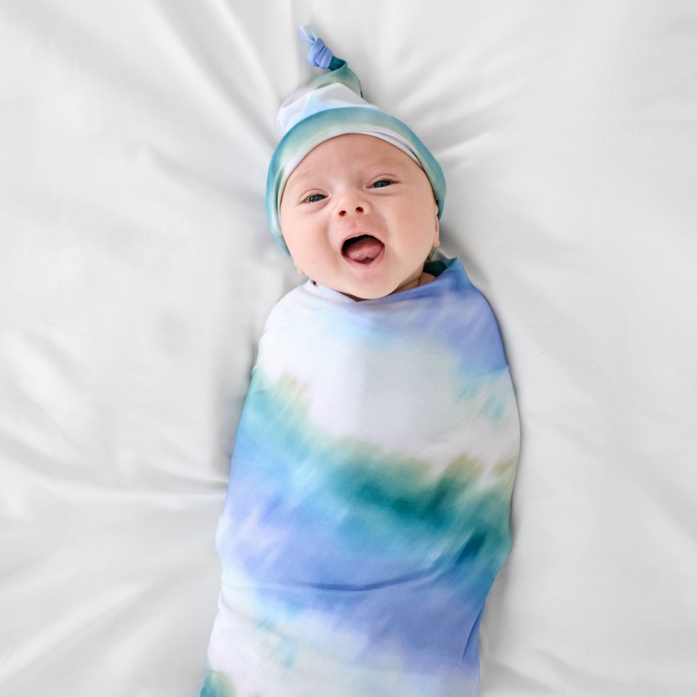 Baby swaddled in the Blue Cosmic Mist Swaddle & Hat Set