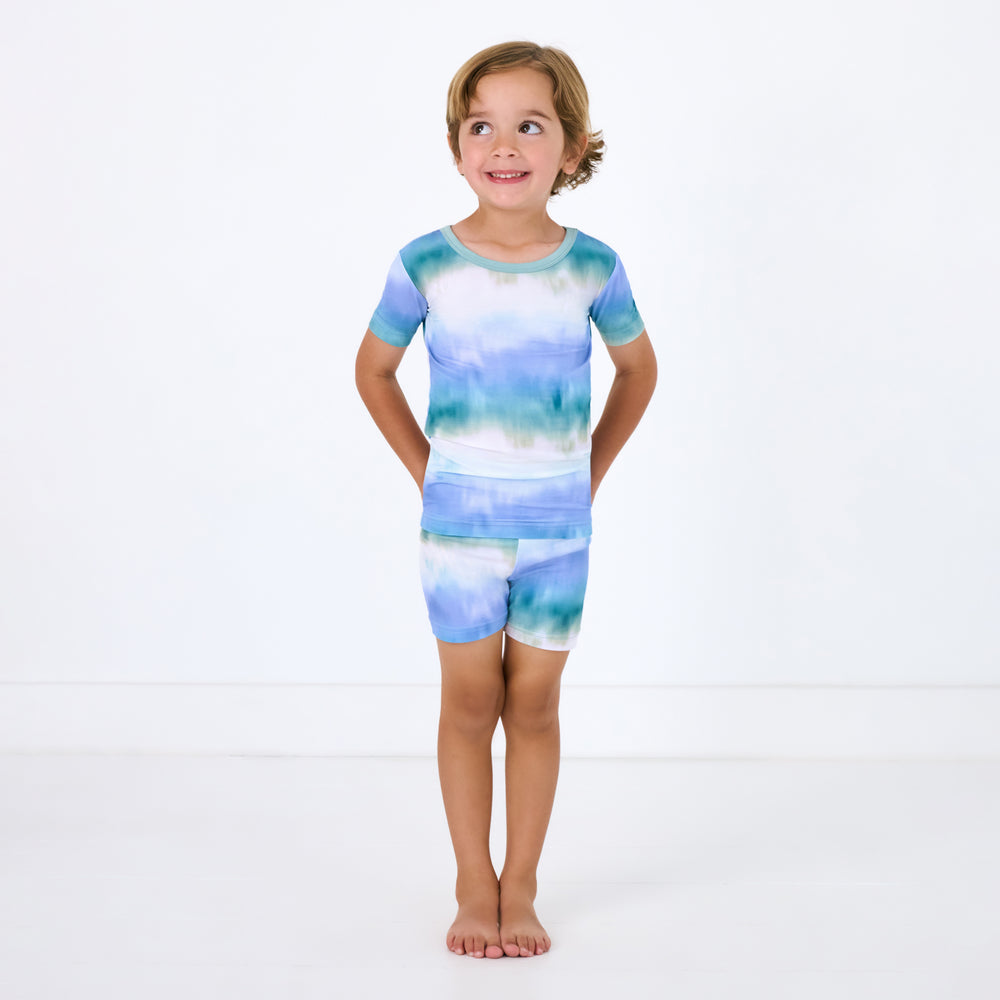 Standing child wearing the Blue Cosmic Mist Two-Piece Short Sleeve & Shorts Pajama Set