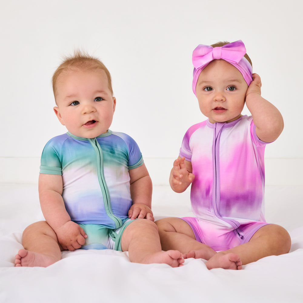 Two sitting children wearing matching Blue and Pink Cosmic Mist Shorty Zippies