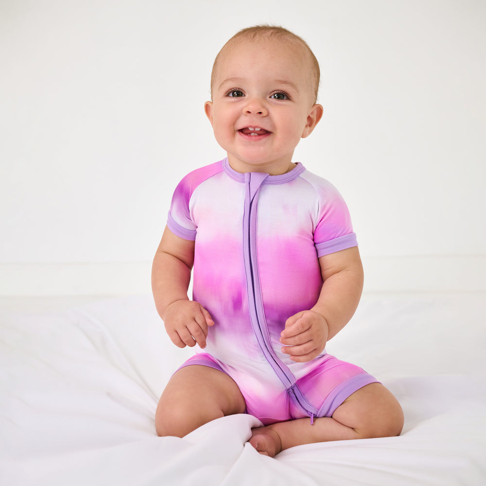 Sitting baby wearing the Pink Cosmic Mist Shorty Zippy