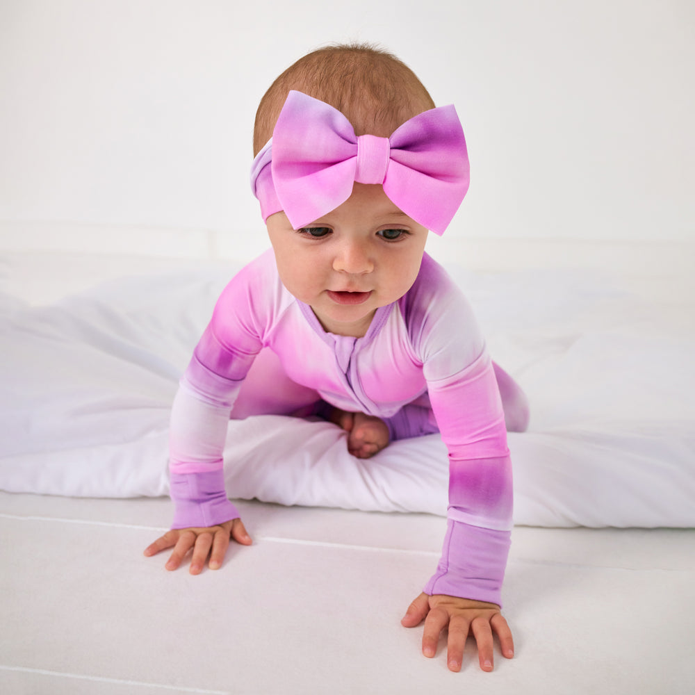 Crawling baby wearing the Pink Cosmic Mist Luxe Bow Headband with a matching bamboo zippy