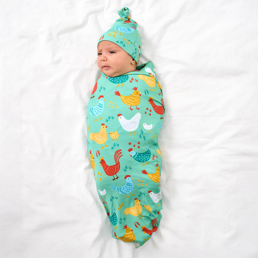 Aerial view of baby wearing the Cozy Coop Swaddle & Hat Set