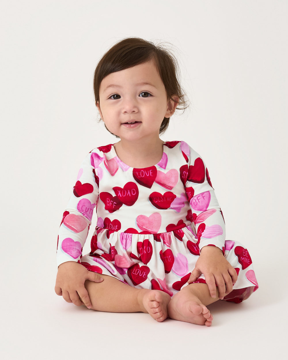 Sitting baby wearing the Candy Cuties Bow Back Dress with Bodysuit