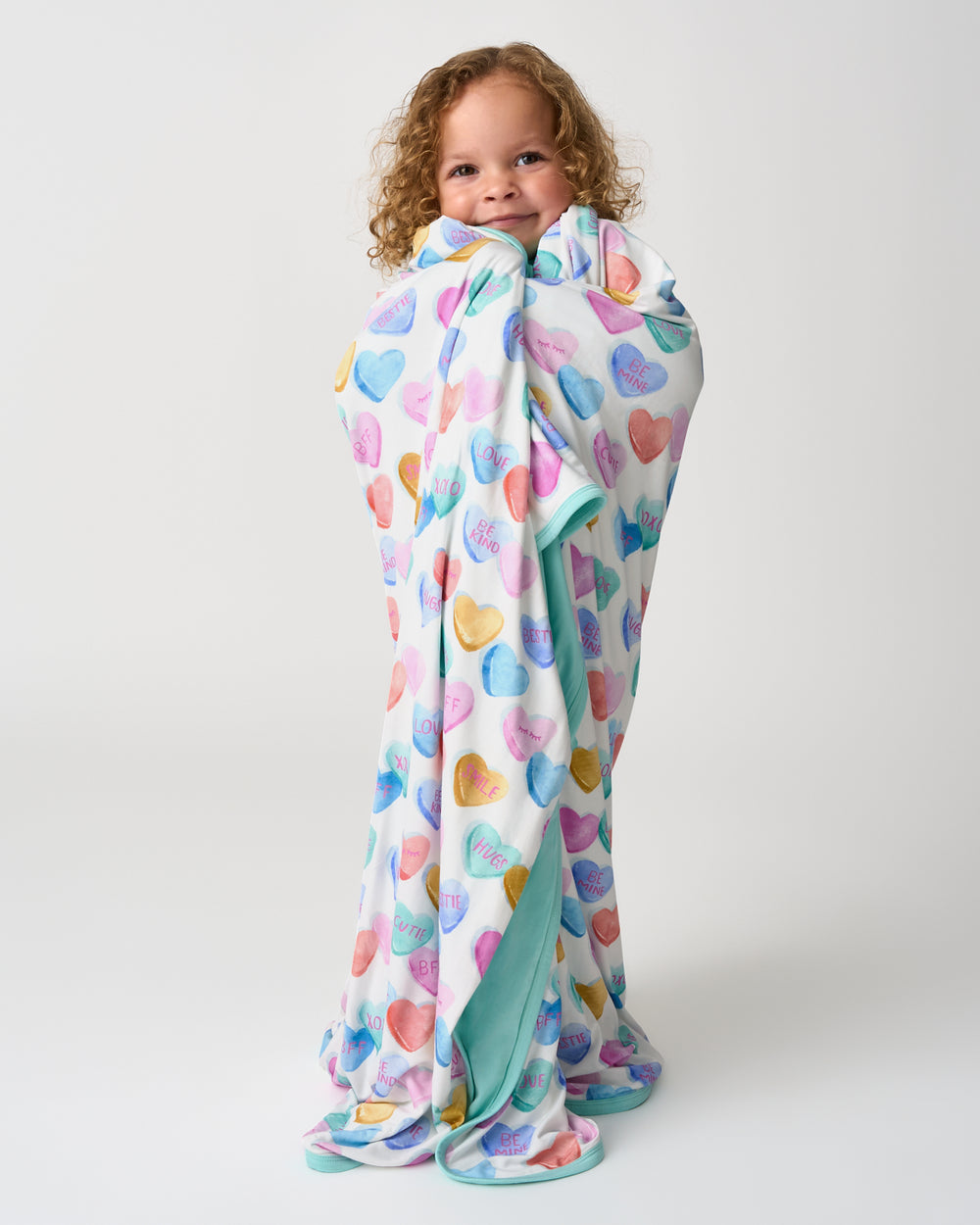 Standing child wrapped in the Candy Cuties Large Cloud Blanket®