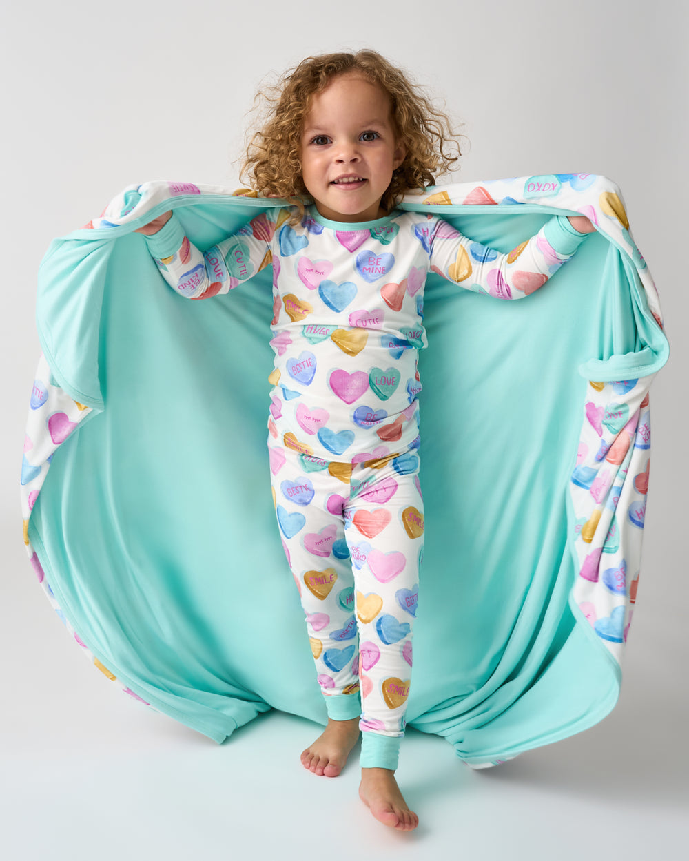 Standing child holding up in the Candy Cuties Large Cloud Blanket® showing the solid blue side 