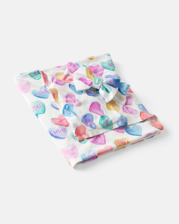 Flat lay of the Candy Cuties Swaddle & Luxe Bow Headband Set