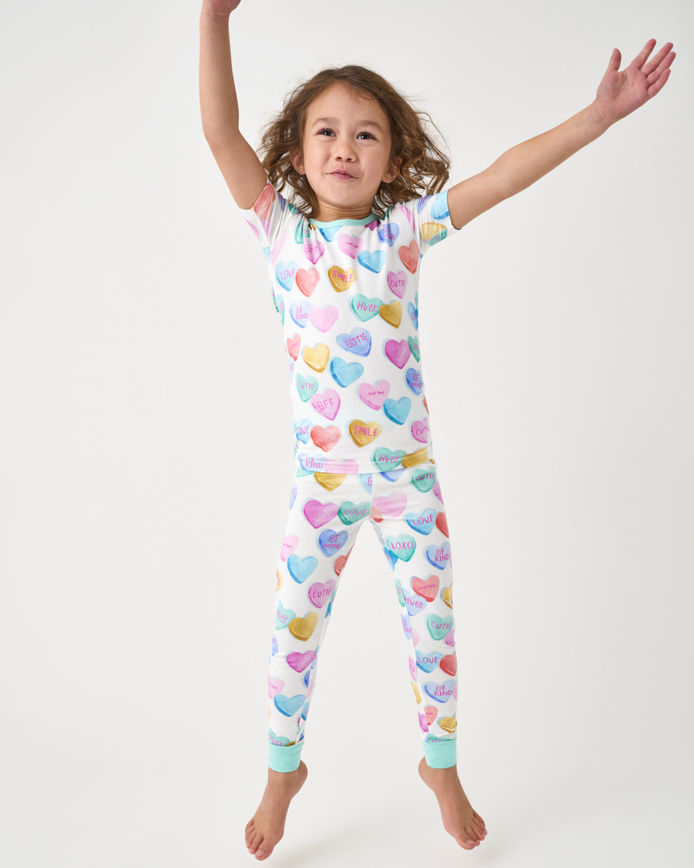 Jumping girl wearing the Candy Cuties Valentines Day Two-Piece Short Sleeve Pajama Set