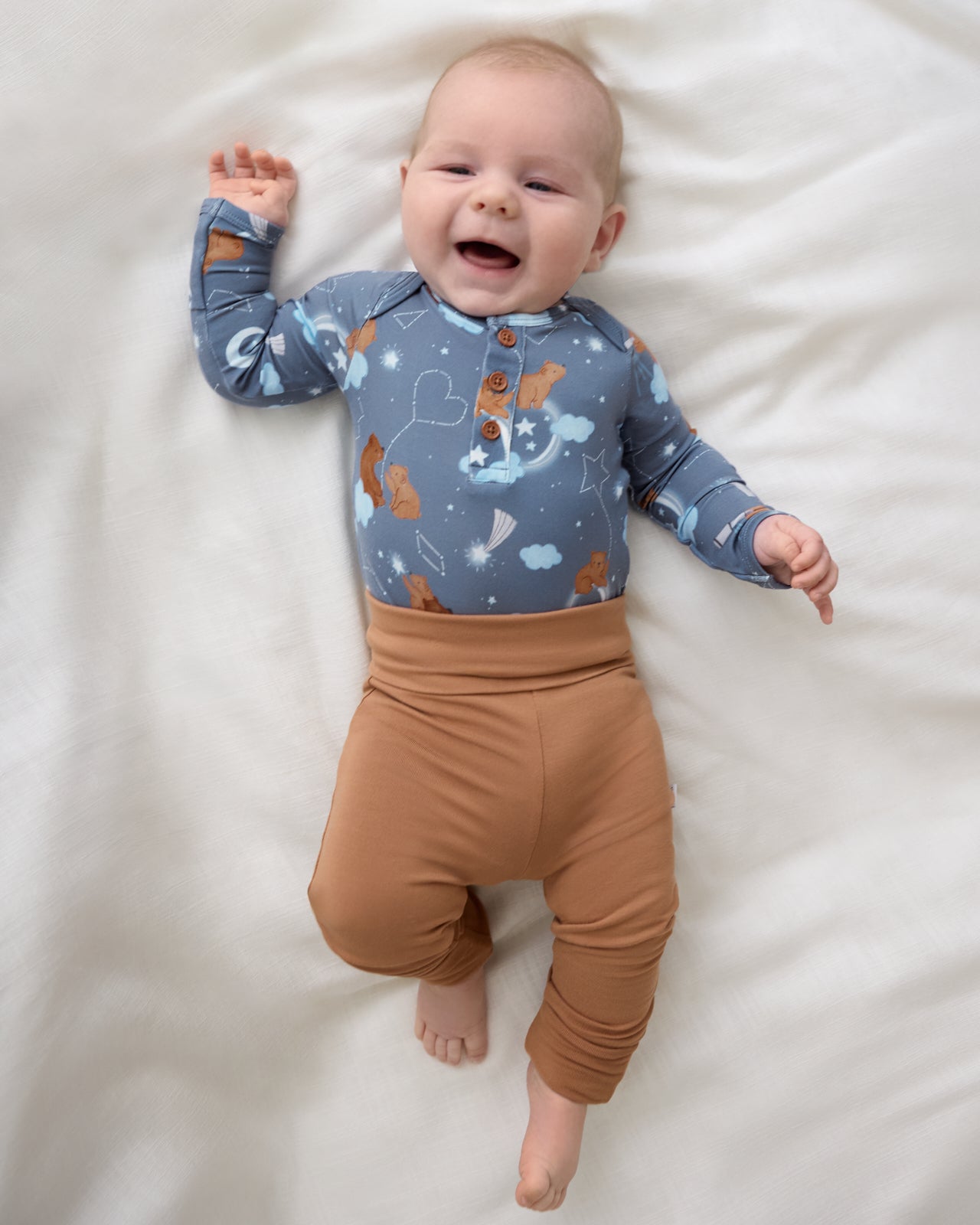Aerial view of newborn wearing the Chestnut Brown Fold Over Legging with the Constellation Cubs henley bodysuit