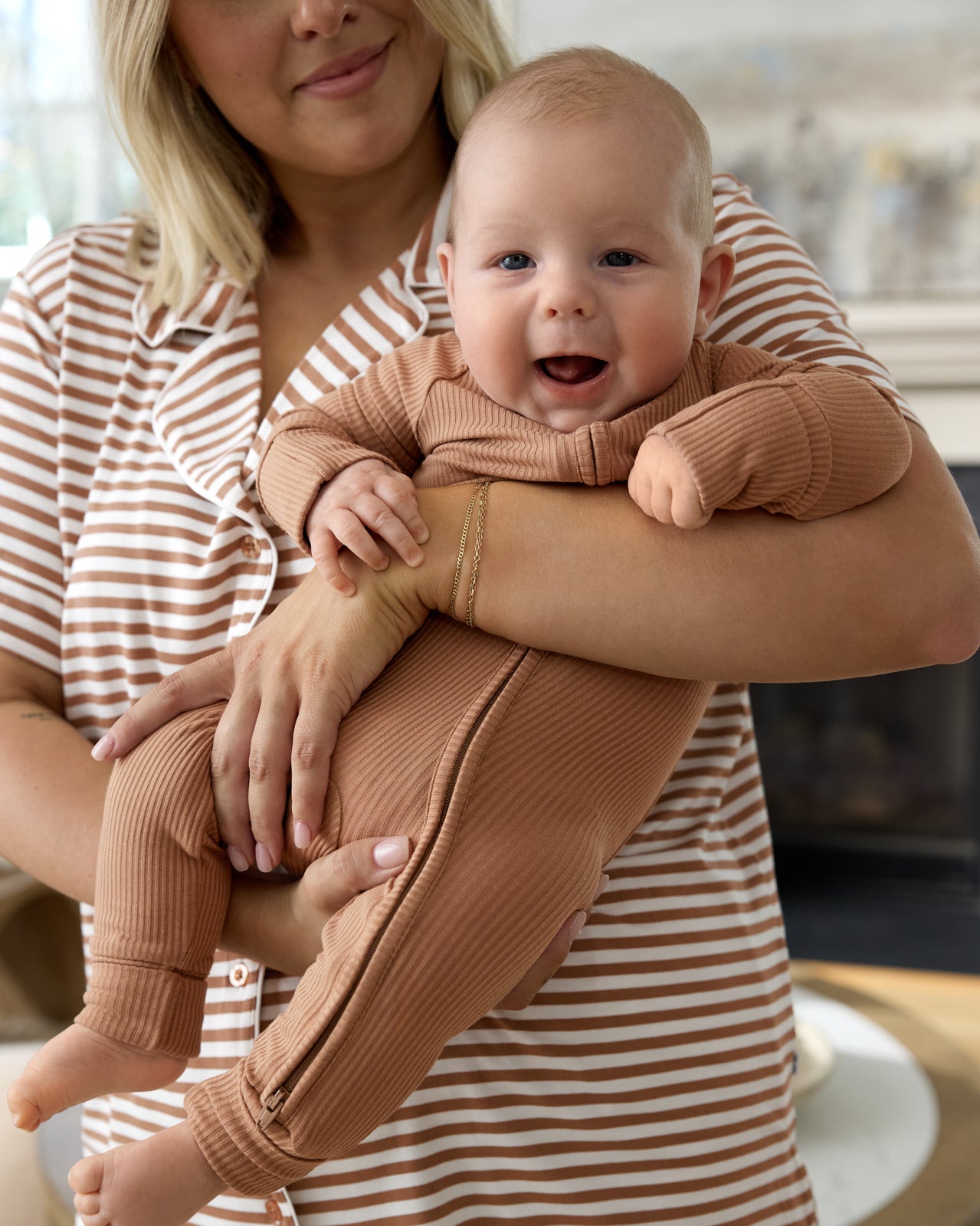 Mother holding baby wearing the Chestnut Brown Ribbed Zippy