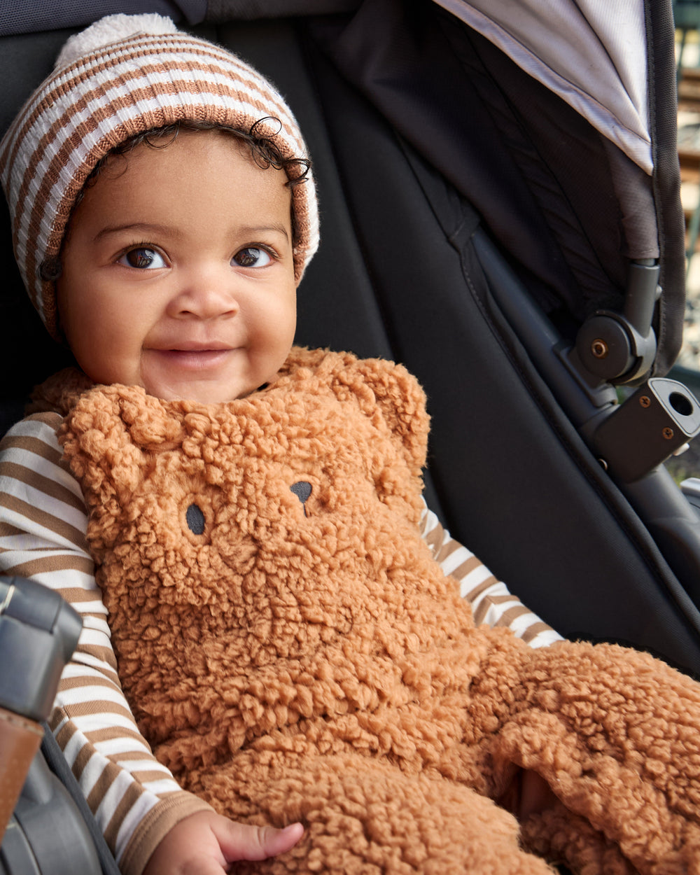 Baby in a stroller wearing the Chestnut Brown Stripe Sweater Beanie Hat and Sherpa Overalls