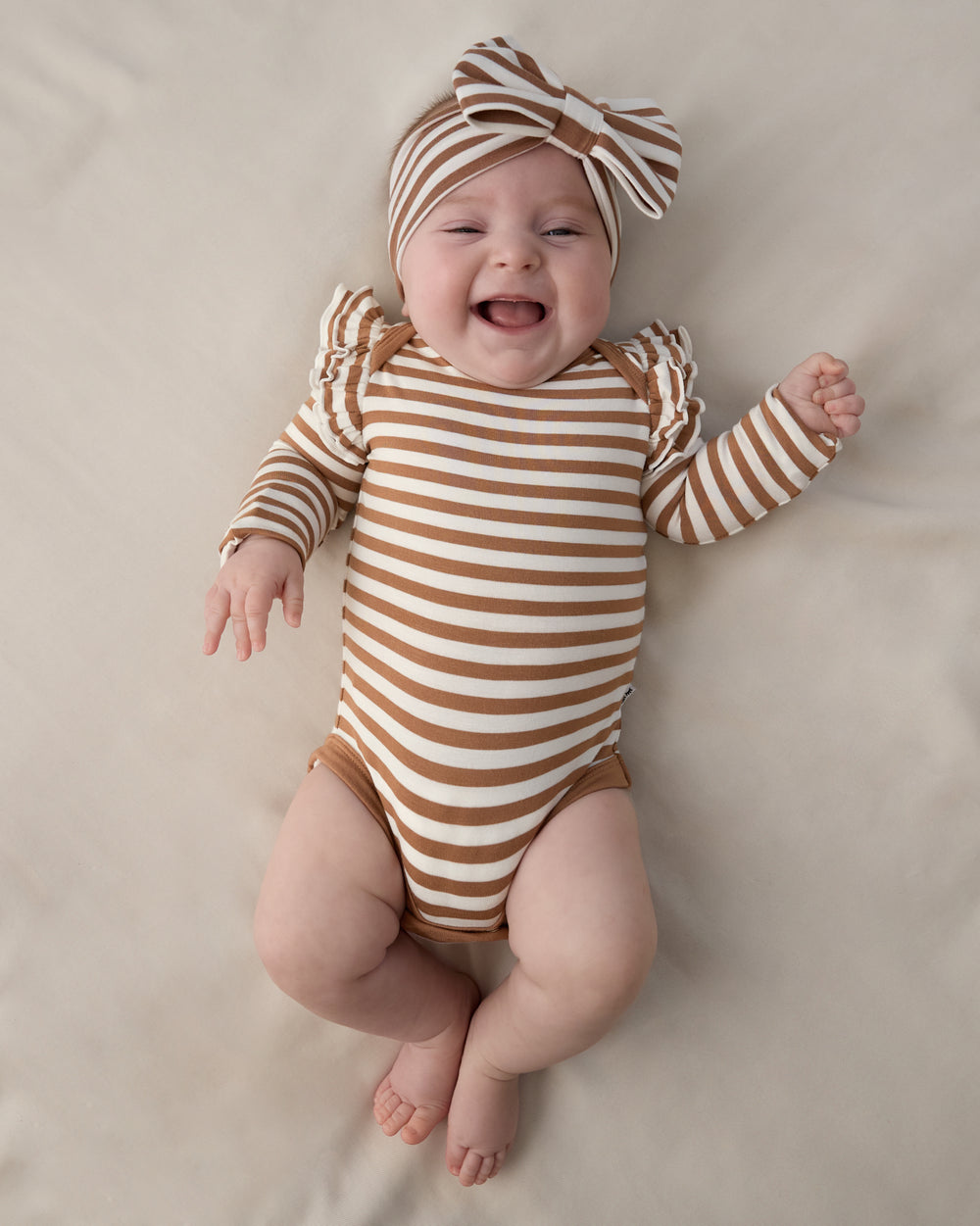 Aerial view of baby wearing the Chestnut Brown Stripe Flutter Bodysuit with a matching bow headband
