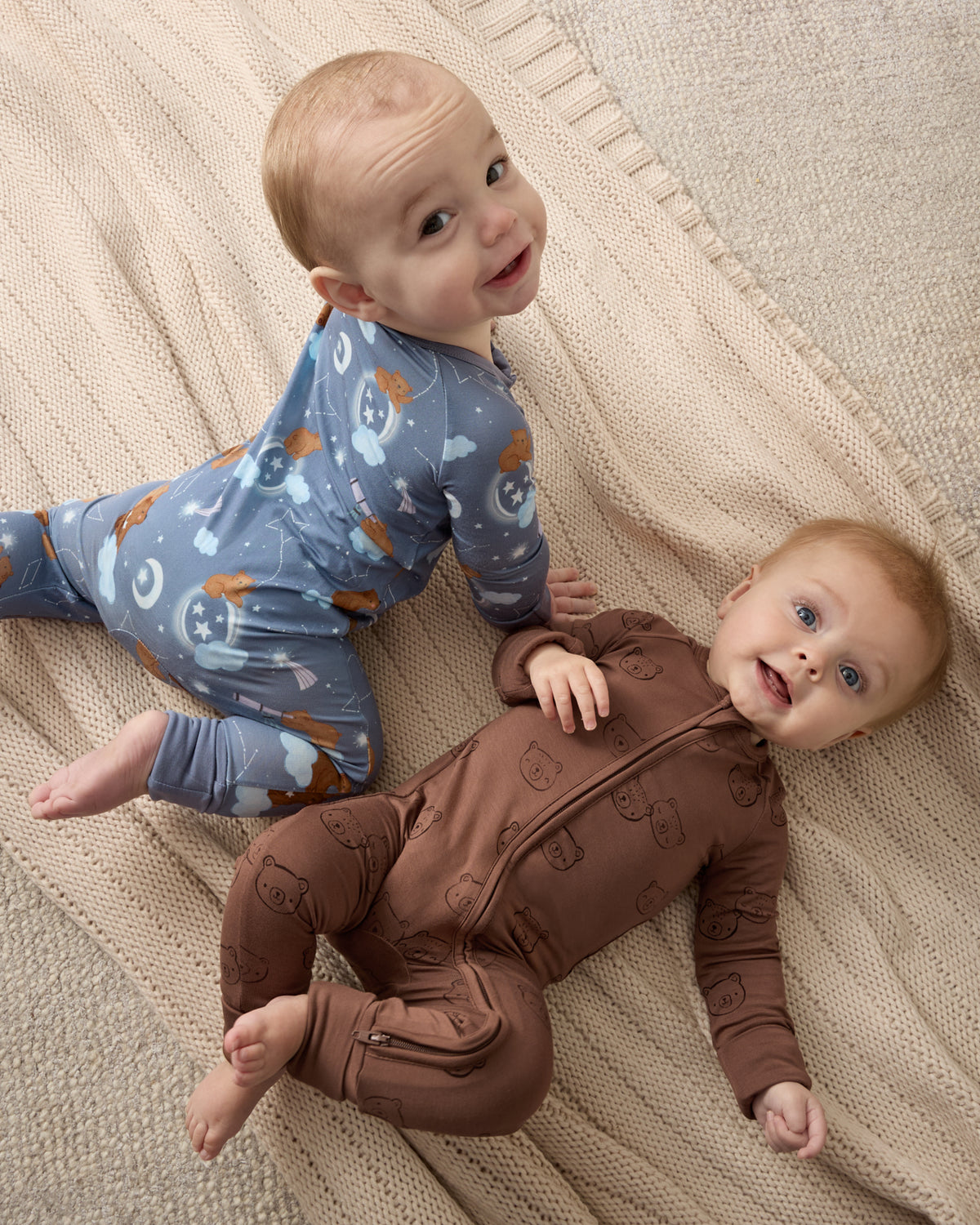Two babies wearing zipper pajamas from the Newborn Capsule