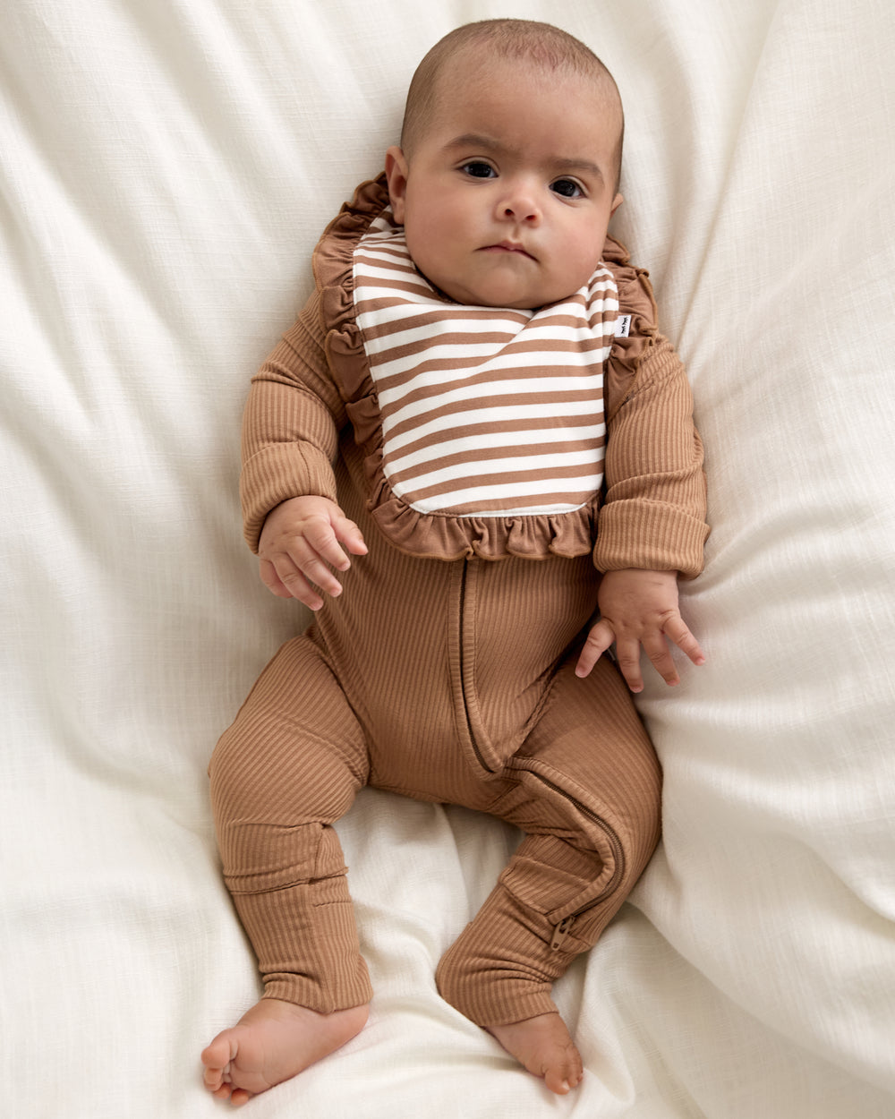 Baby wearing the Chestnut Brown Stripe Ruffle Bib with a ribbed zippy