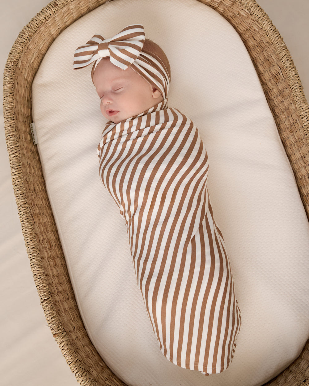 Aerial view of baby wearing the Chestnut Brown Stripe Swaddle & Luxe Bow Headband Set