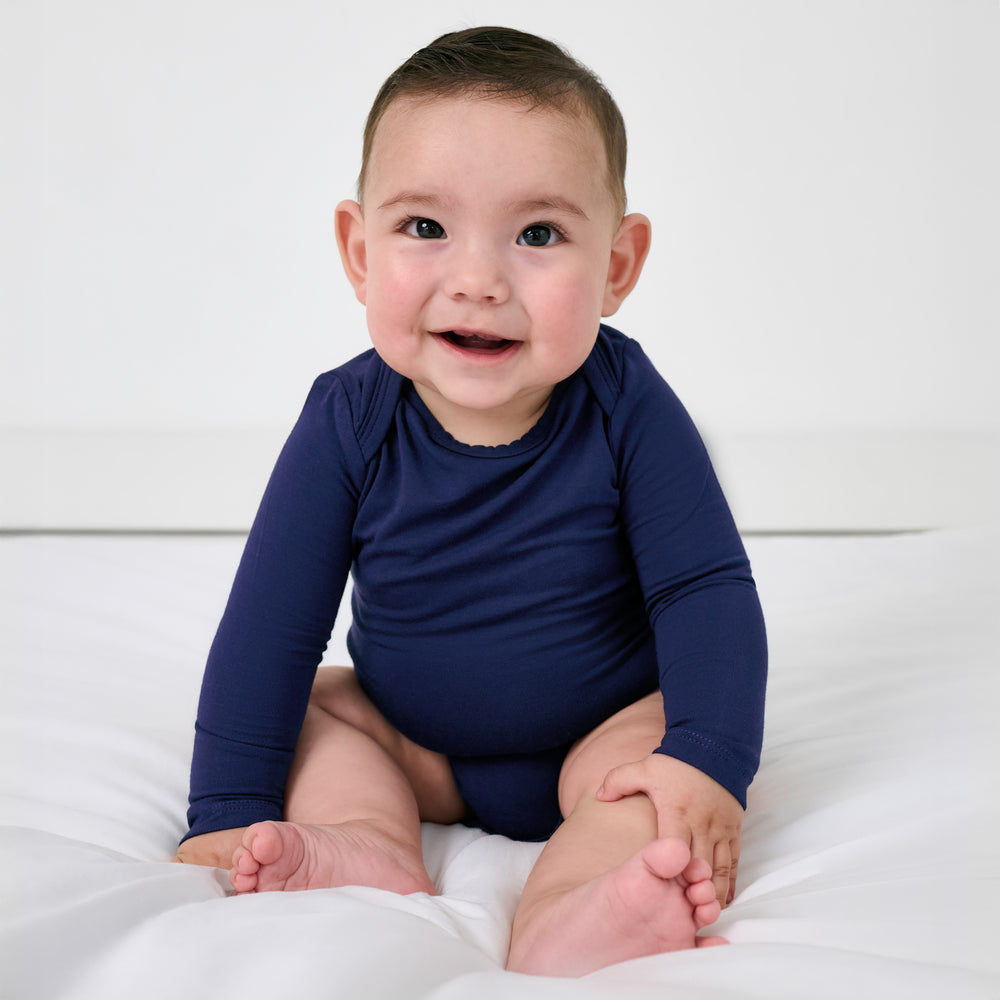 Sitting child wearing the Classic Navy Long Sleeve Bodysuit