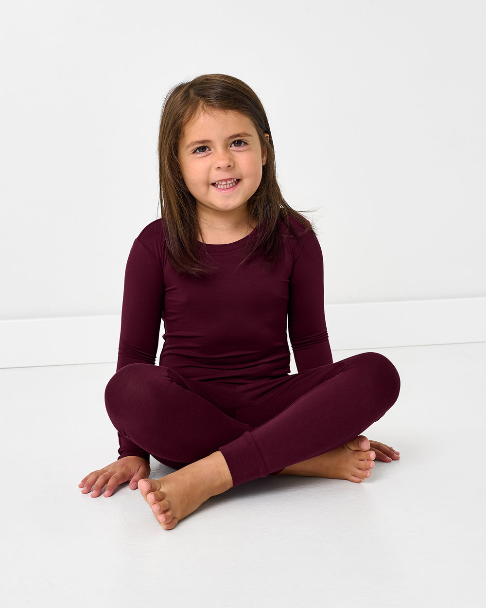 Sitting girl wearing the Classic Burgundy Two-Piece Pajama Set