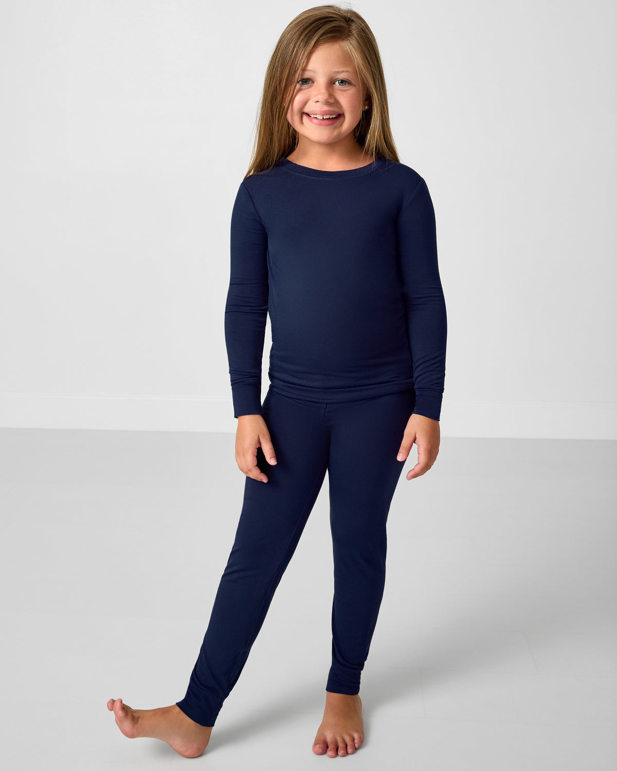 Child wearing a navy long-sleeve shirt and pants on a white background