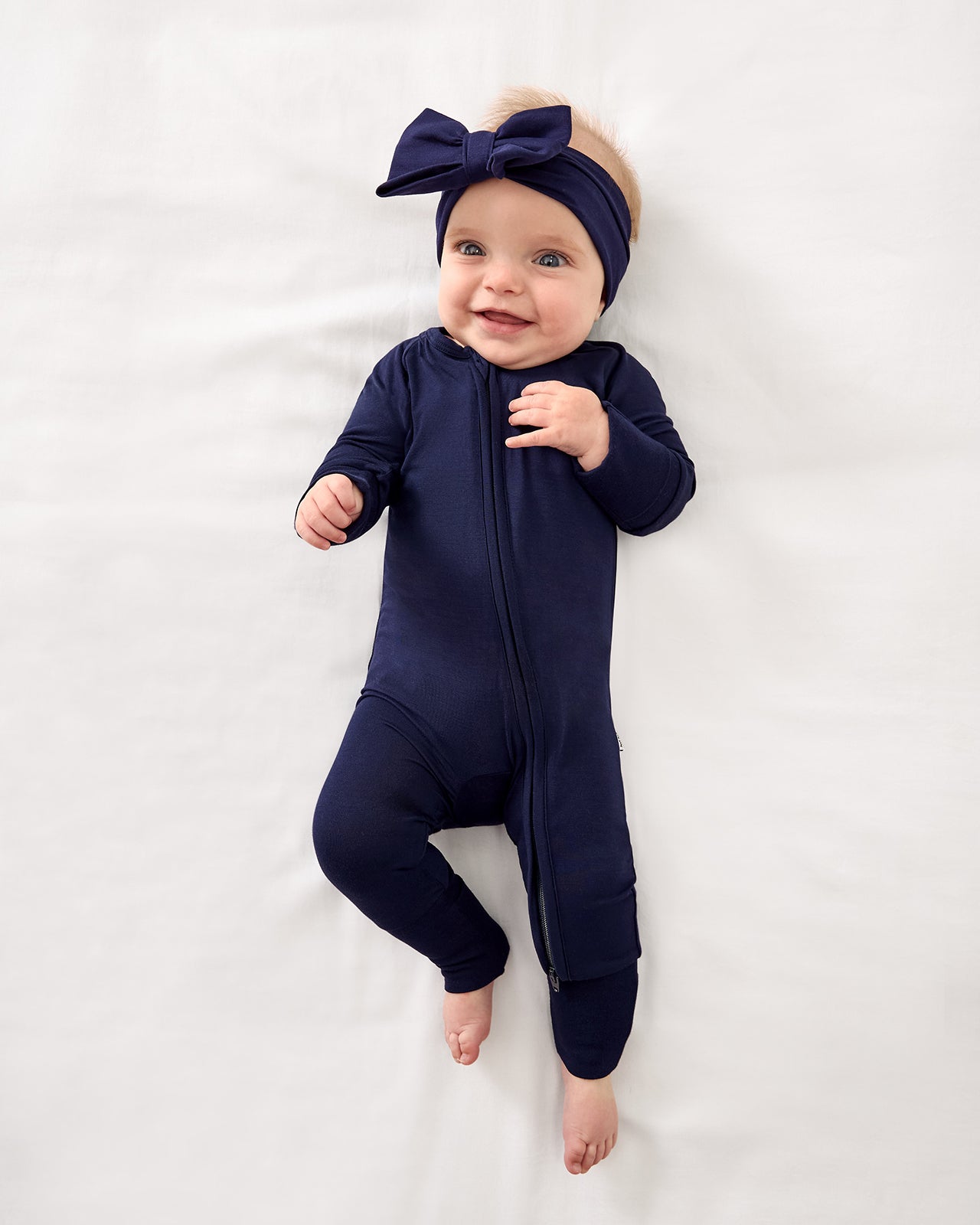Baby wearing the Classic Navy Luxe Bow Headband with a Classic Navy Zippy