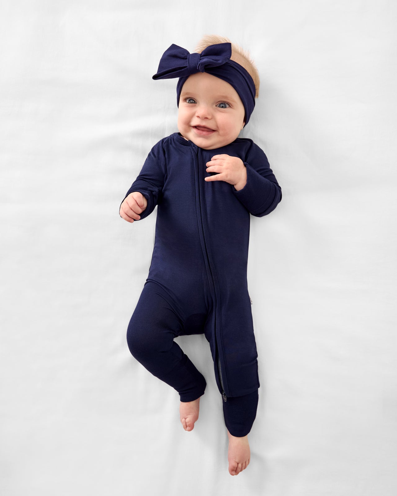 Baby wearing the Classic Navy Luxe Bow Headband with a Classic Navy Zippy