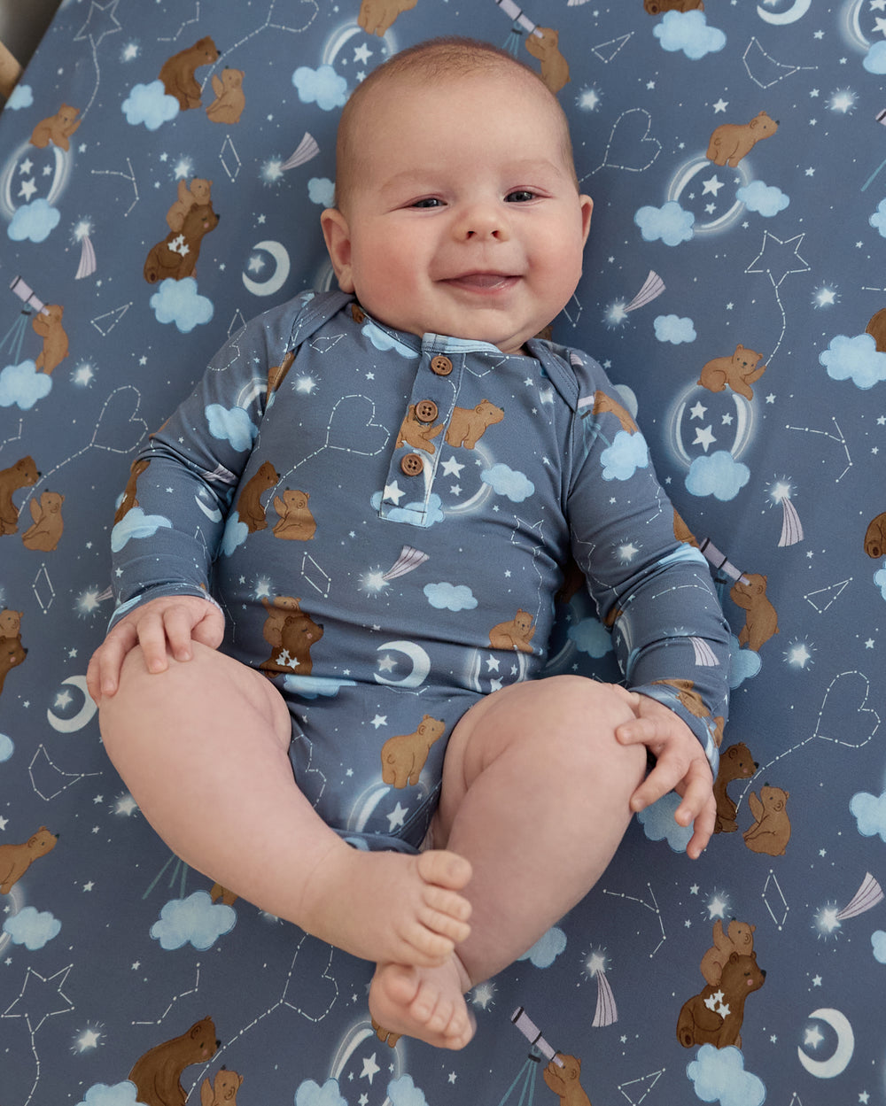 Aerial view of newborn wearing the Constellation Cubs Henley Bodysuit on the matching crib sheet