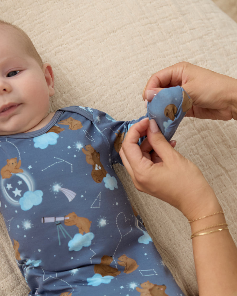 Adult demonstrating the mitten feature on the Constellation Cubs Infant Gown