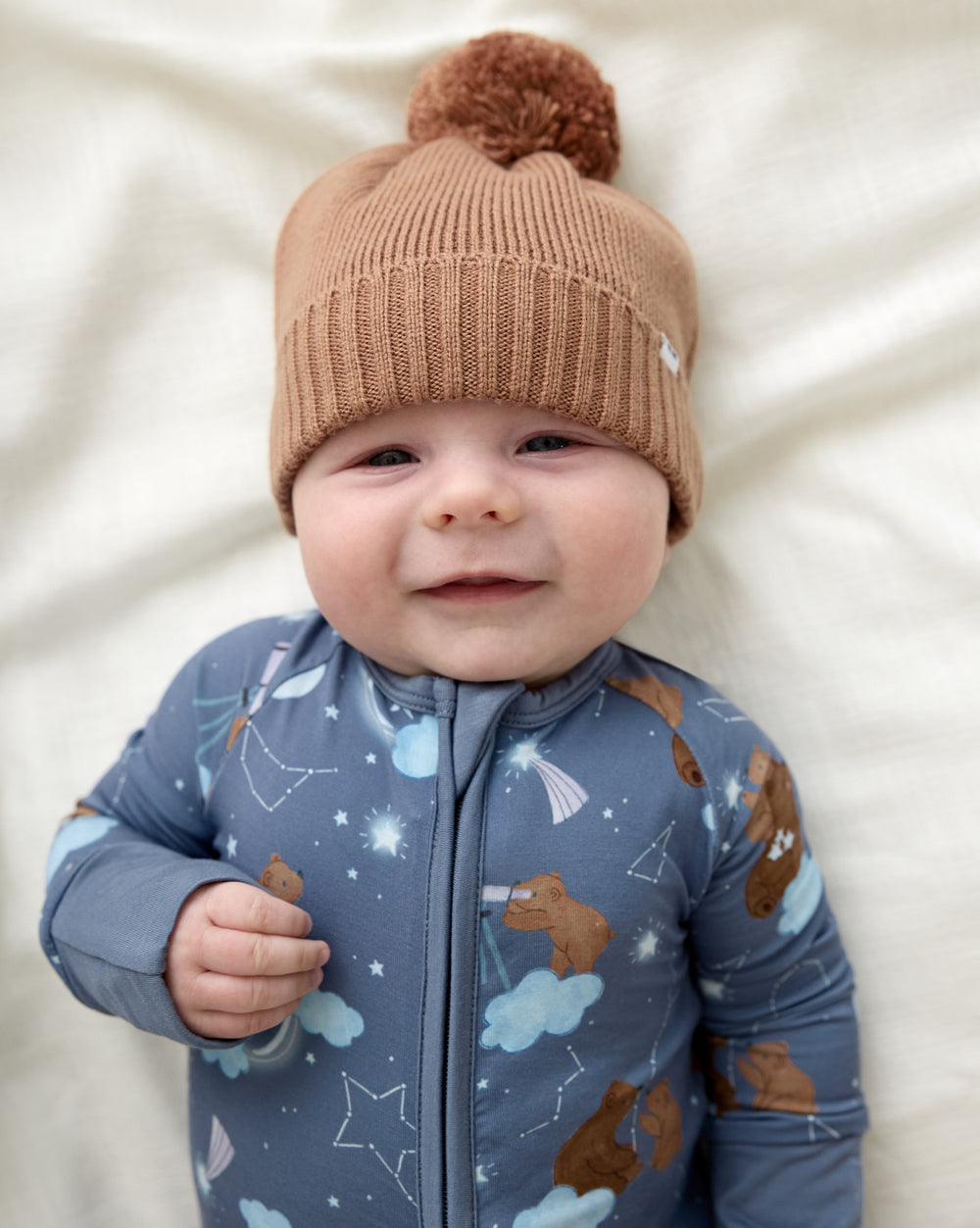 Newborn wearing the Chestnut Brown Sweater Beanie Hat with the Constellation Cubs zippy