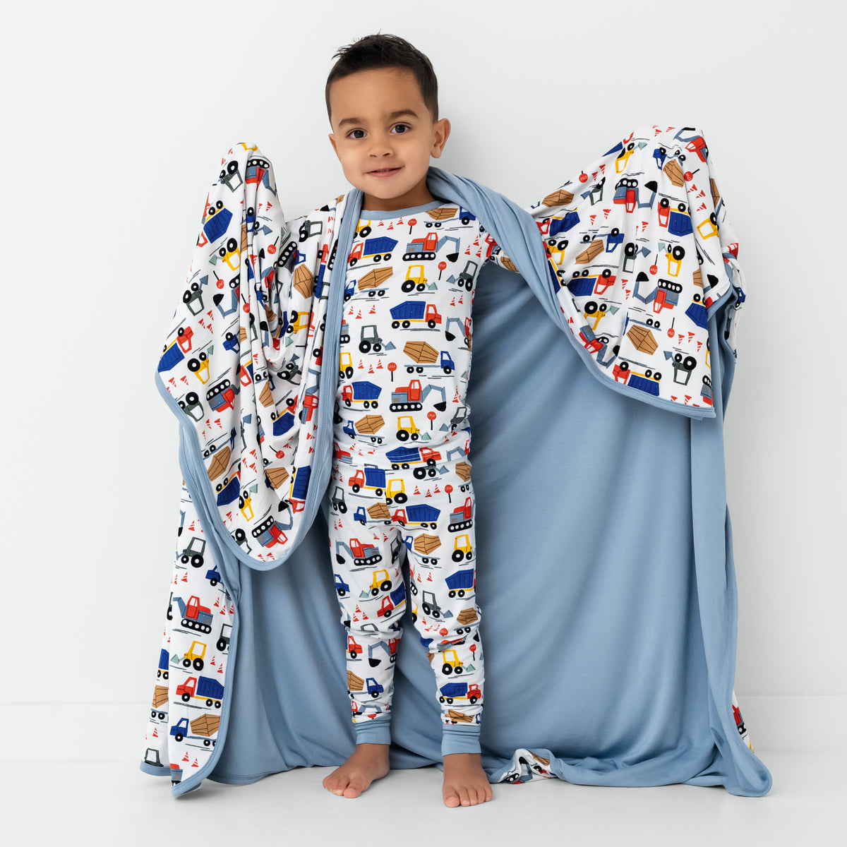 Standing child holding up the Construction Large Cloud Blanket®