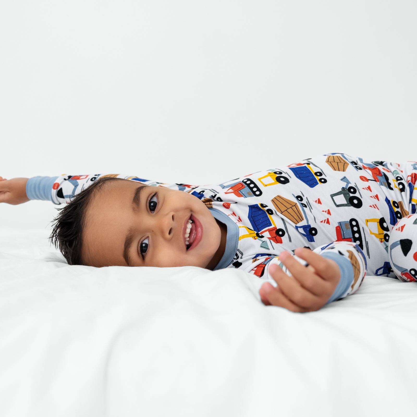 Laying child wearing the Construction Two-Piece Pajama Set