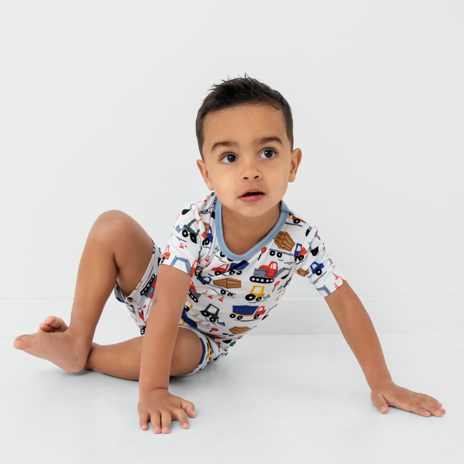 Sitting child wearing the Construction Two-Piece Short Sleeve & Shorts Pajama Set