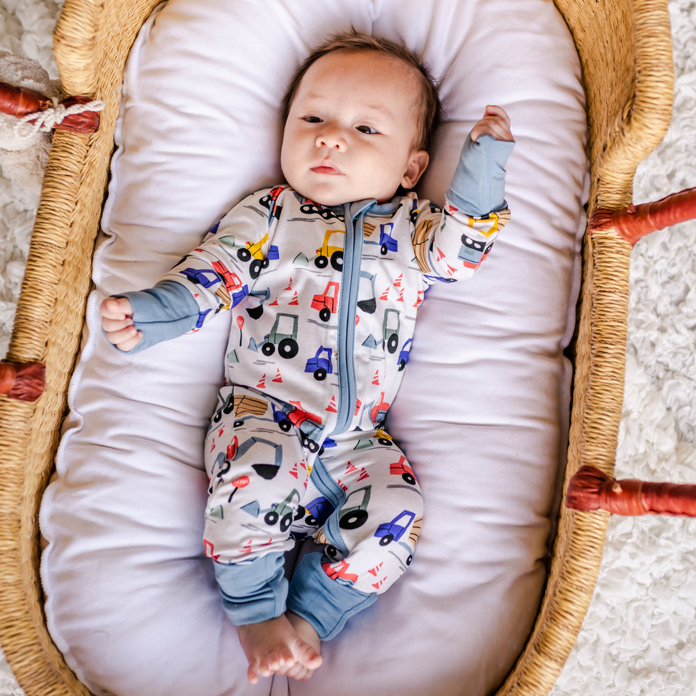 Baby in basket laying down wearing the construction zippy