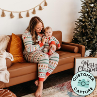 Customer Capture image of a mother and child matching in Fair Isle pajamas. Mom is wearing women's Fair Isle pajama top and matching women's pajama pants, her child is wearing a matching zippy