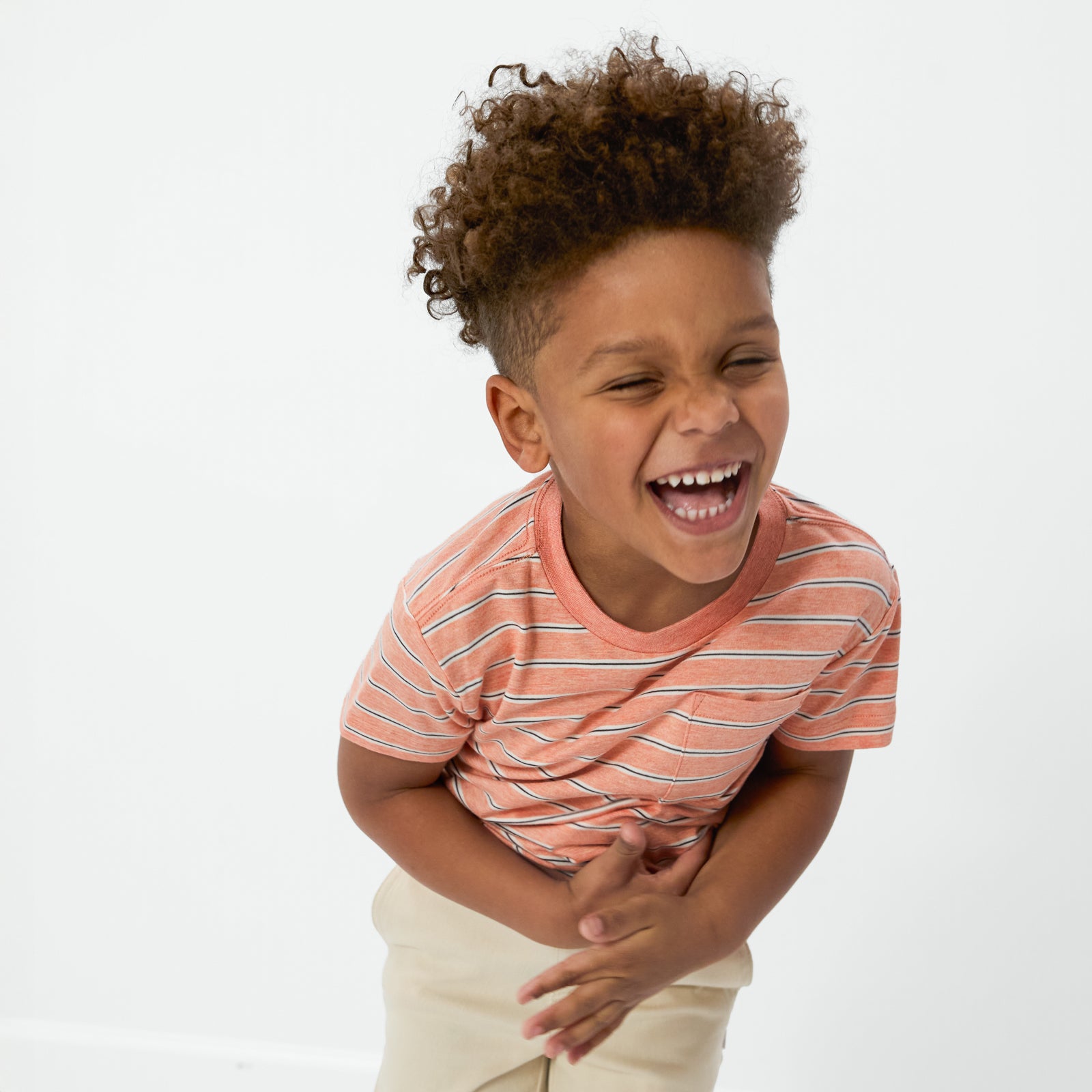 Laughing child wearing the Coral Stripes Relaxed Pocket Tee