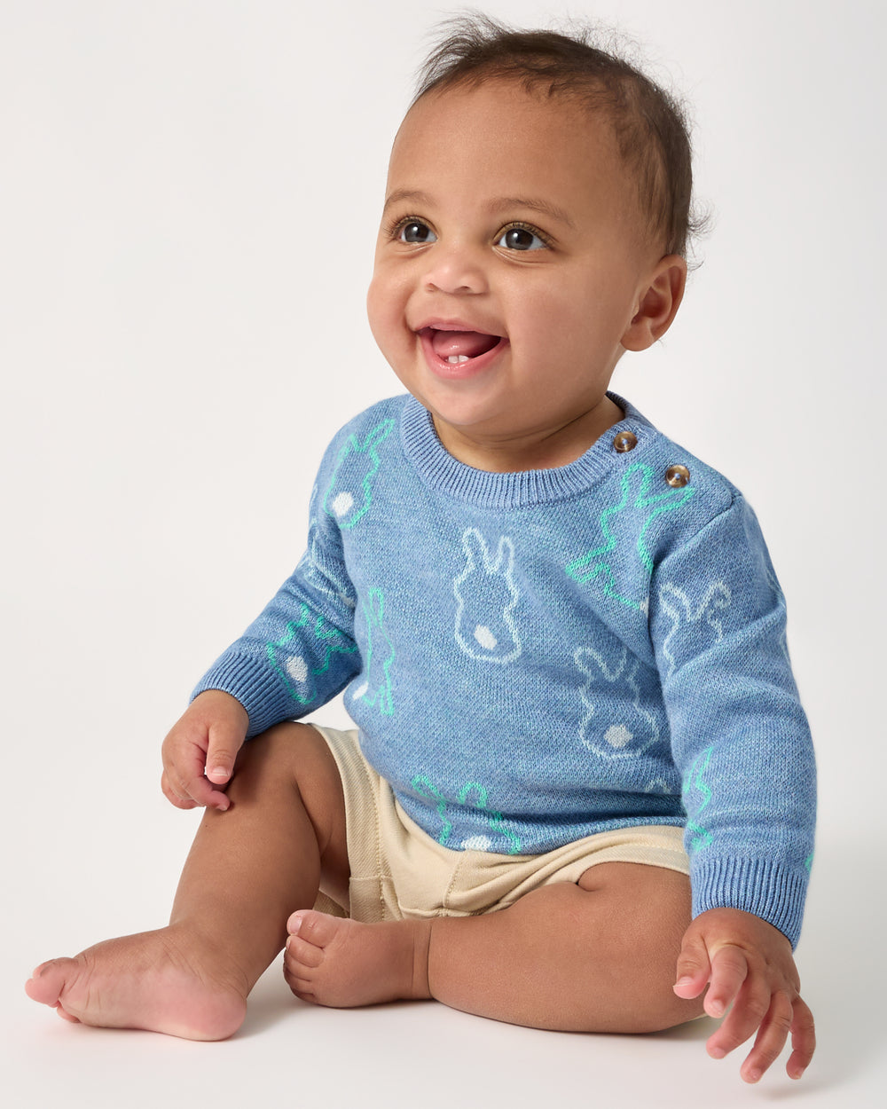 Sitting baby wearing the Cozy Cottontails Baby Sweater
