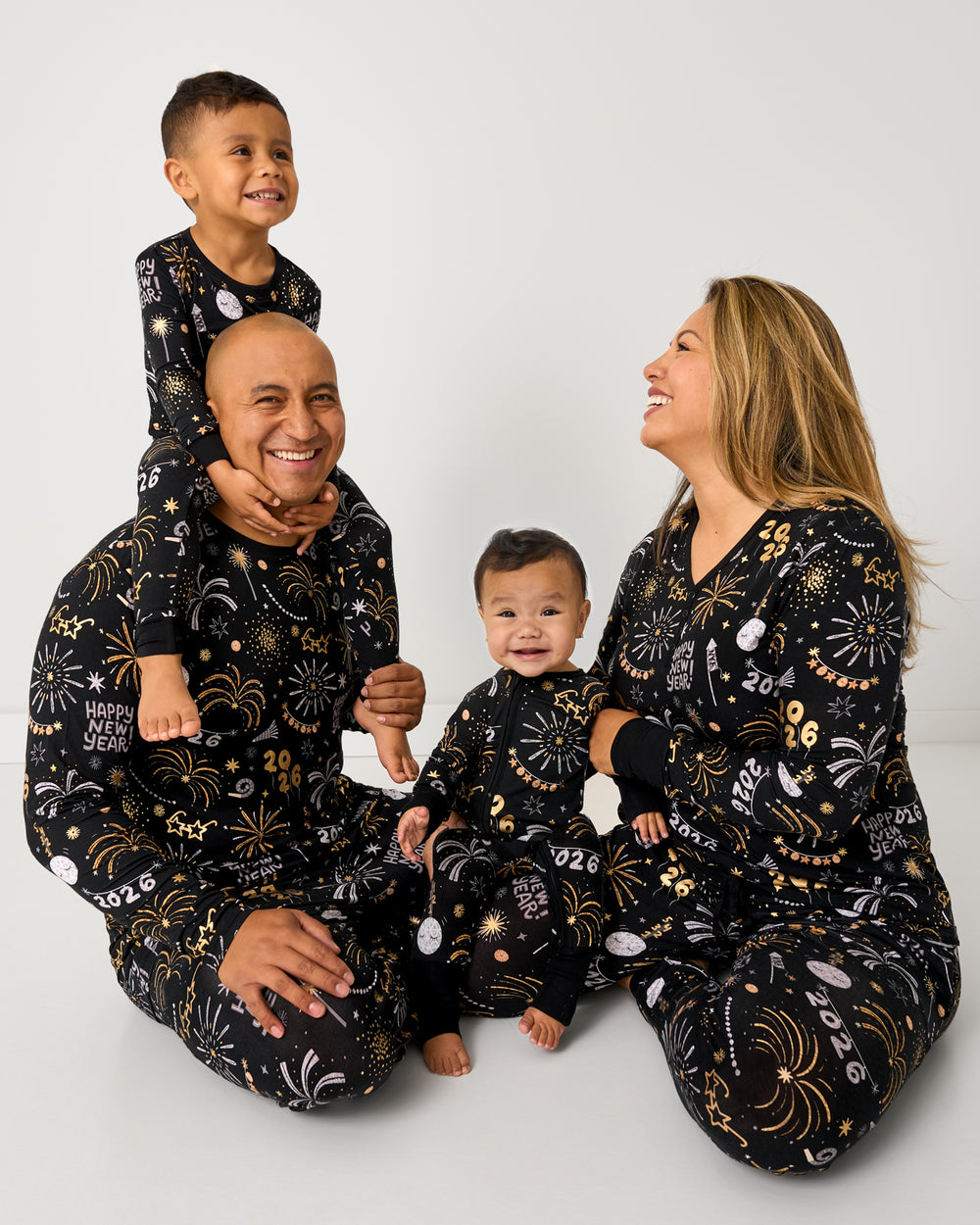 Sitting family of four wearing matching Cozy Countdown New Years Pajamas