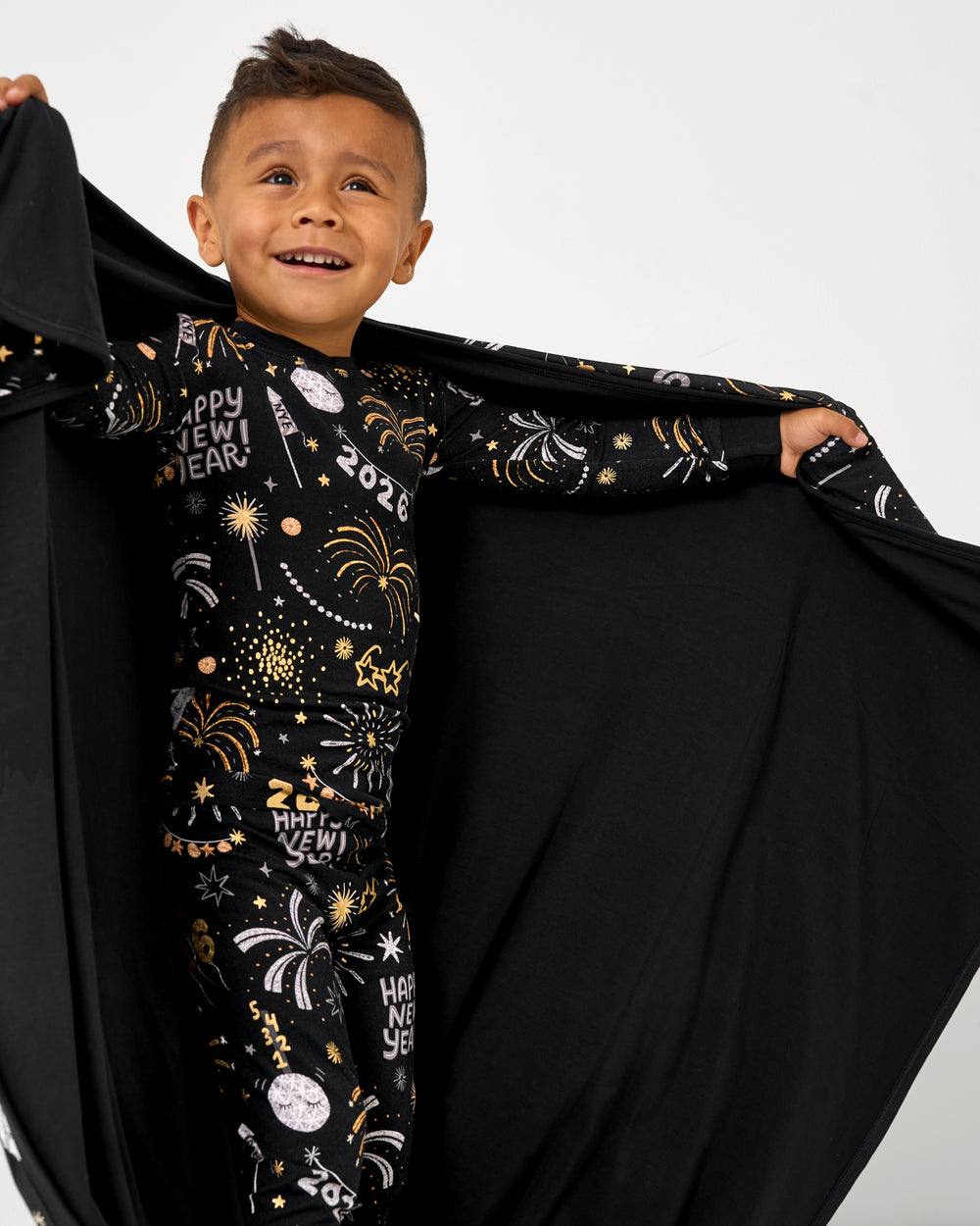 Boy holding up the xCozy Countdown Large Cloud Blanket® showing the solid black side