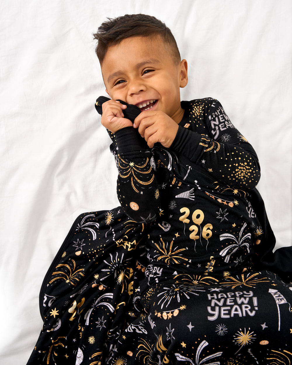 Aerial view of boy wrapped in the Cozy Countdown Large Cloud Blanket® on a white bed