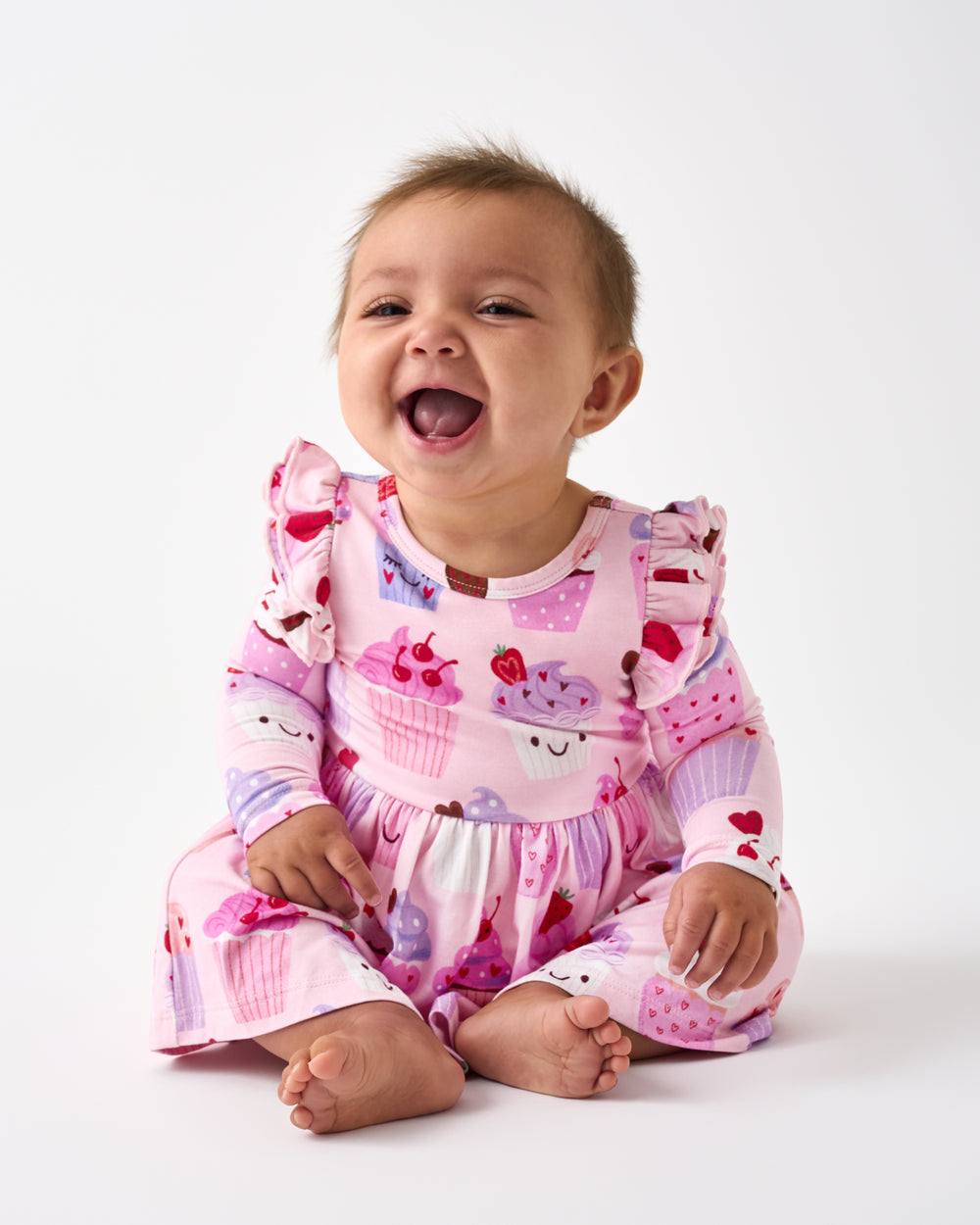 Sitting baby wearing the Cupcake Kisses Flutter Skater Dress with Bodysuit