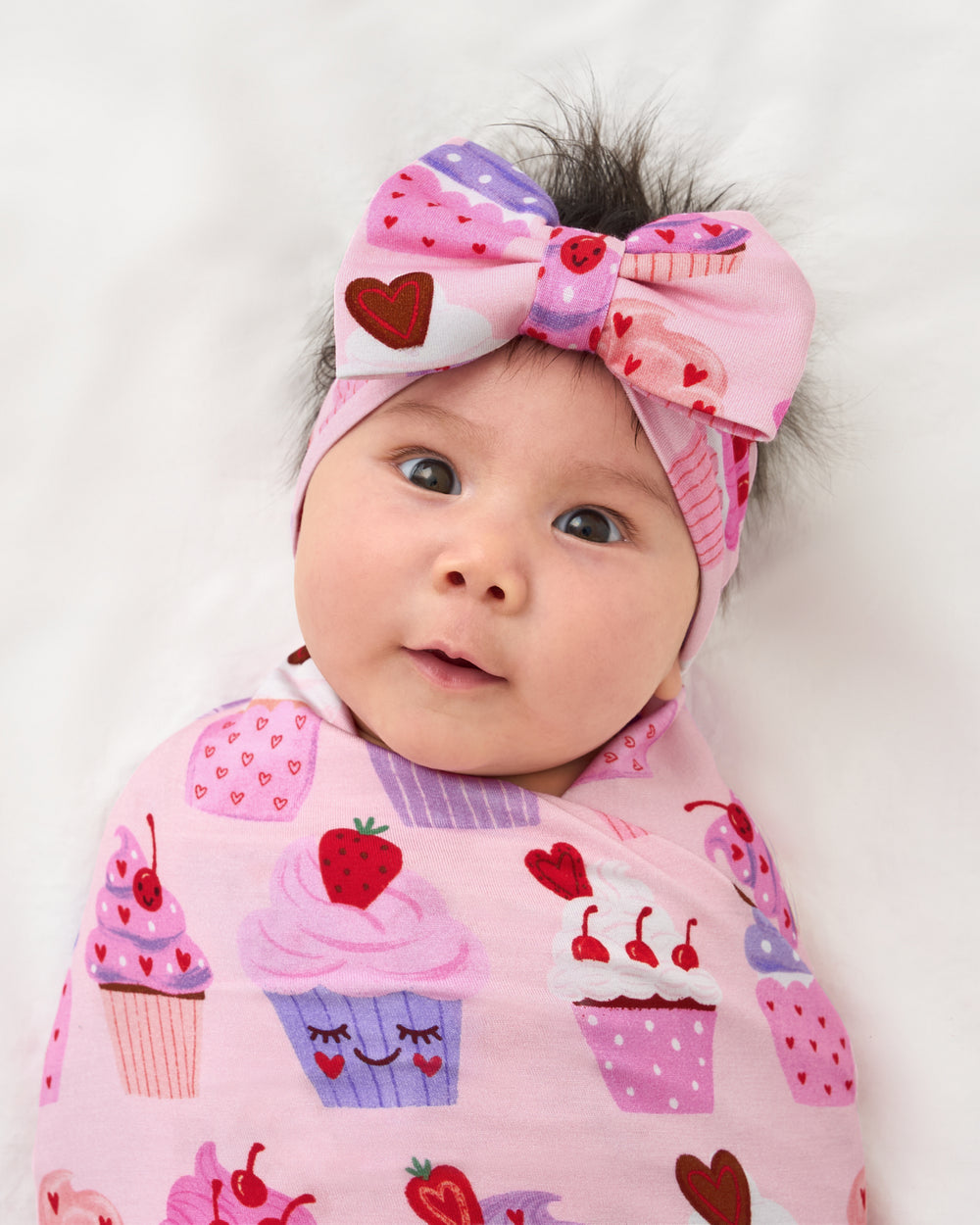 Close up of baby wearing the Cupcake Kisses Swaddle & Luxe Bow Headband Set