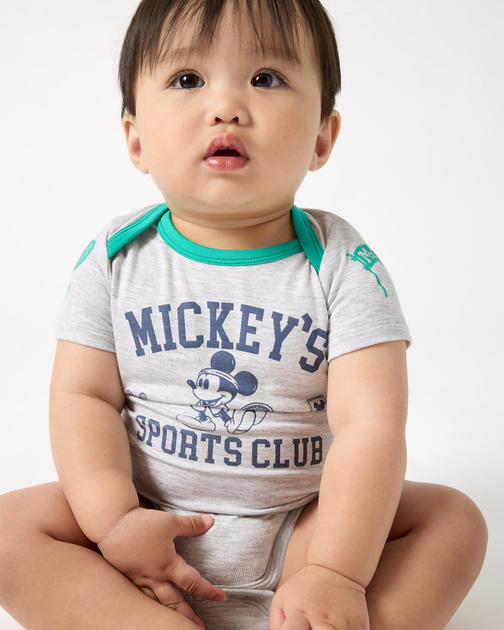 Close up of sitting baby wearing the Disney Mickey Mouse Sports Club Bodysuit