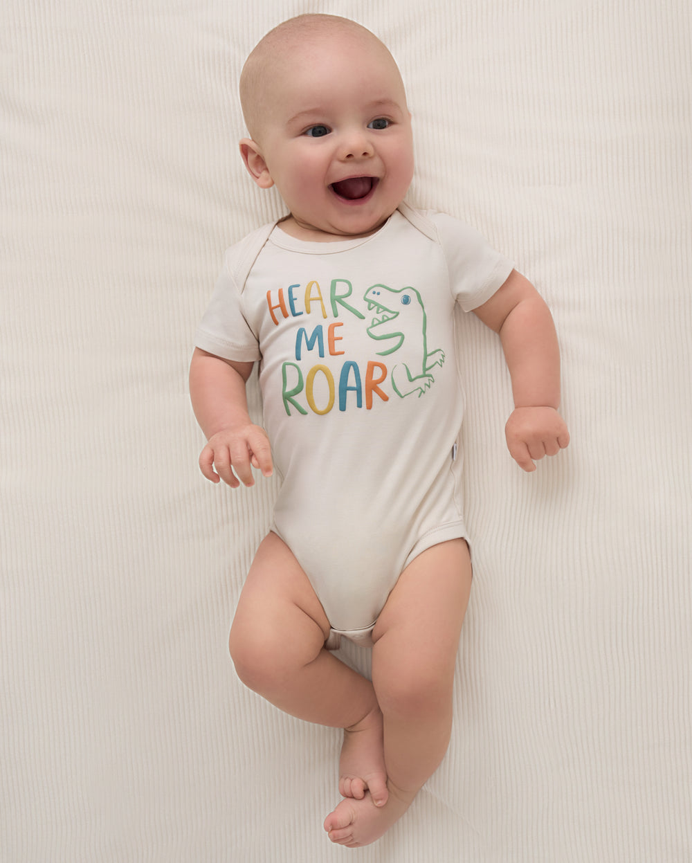 Aerial view of newborn wearing the Hear Me Roar Bodysuit