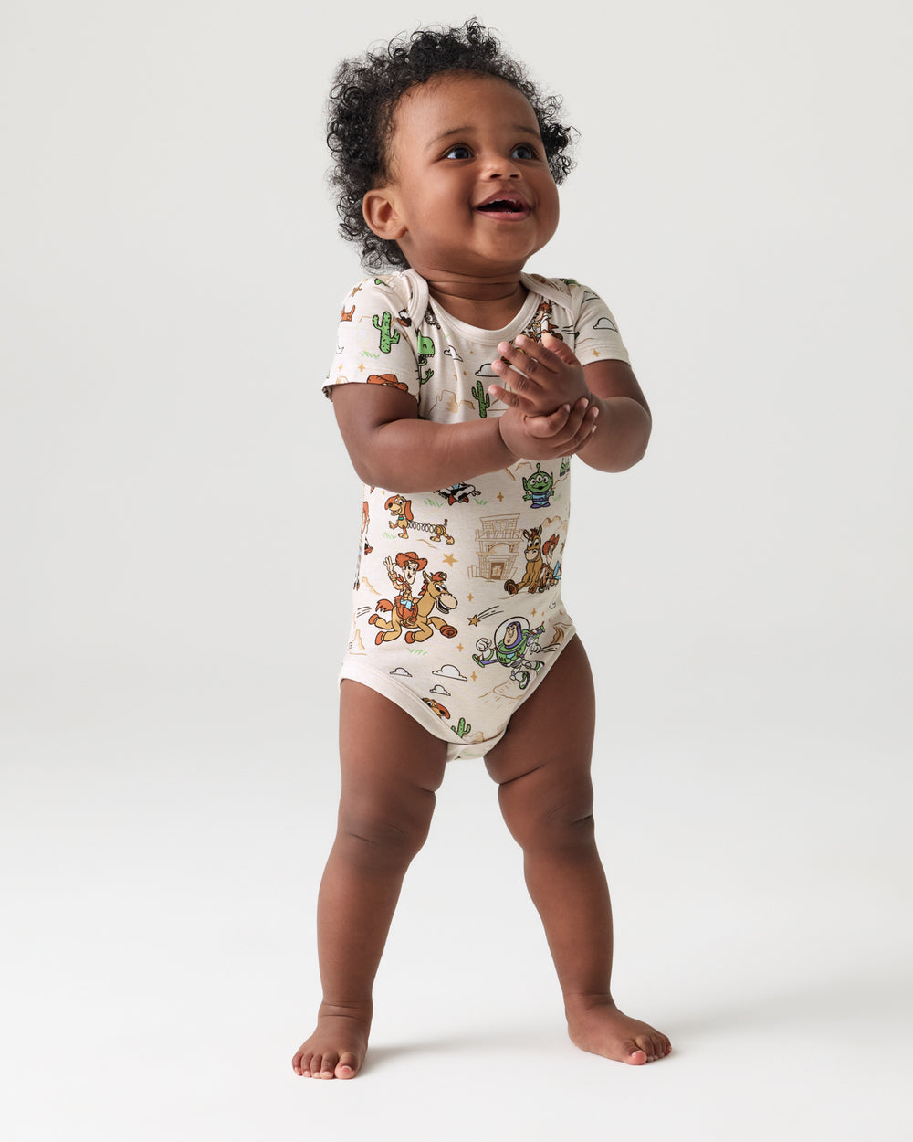 Standing toddler wearing the Disney & Pixar Woody's Wild West Bodysuit
