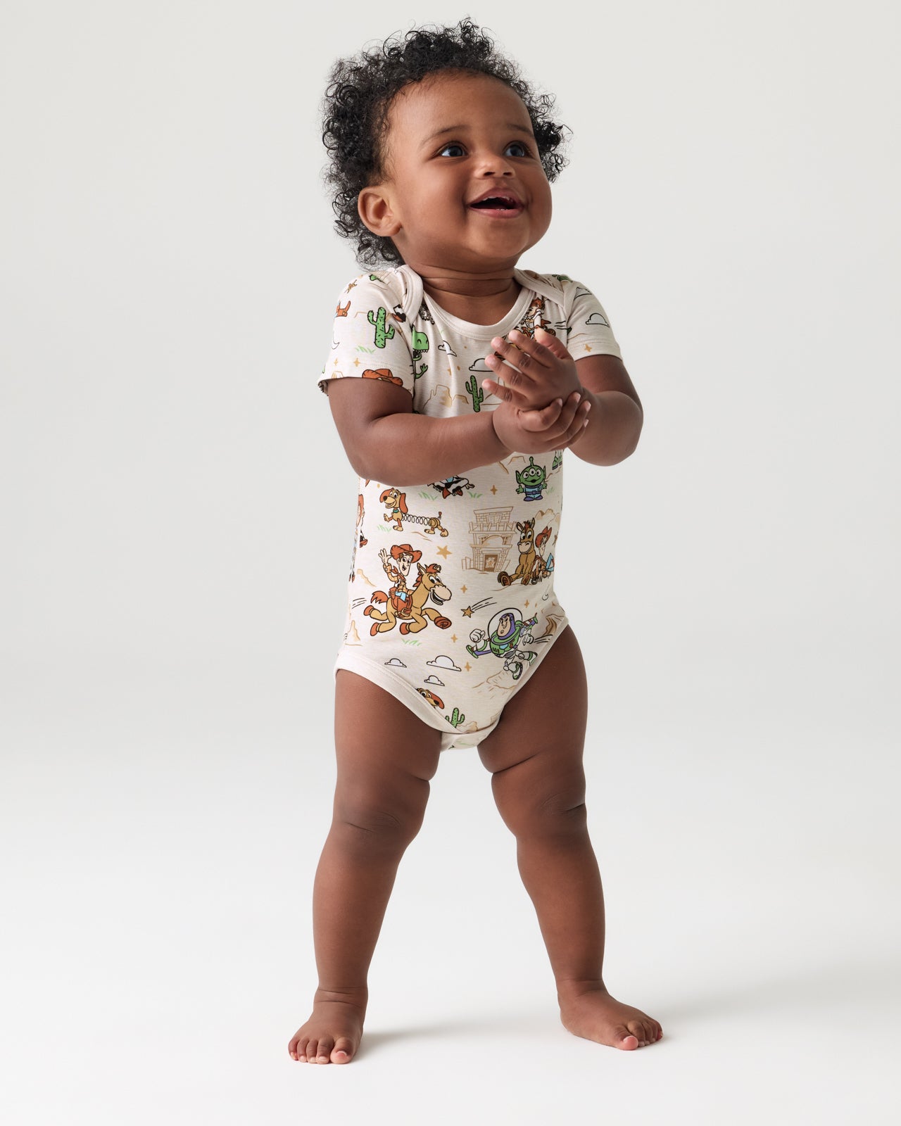 Standing toddler wearing the Disney & Pixar Woody's Wild West Bodysuit