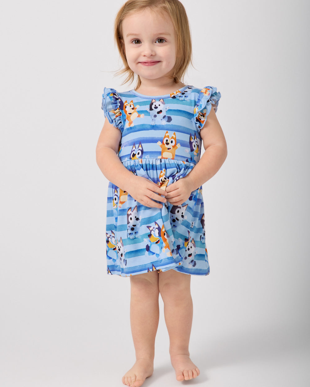 Standing toddler wearing the Bluey Dance All Day Flutter Skater Dress with Bodysuit